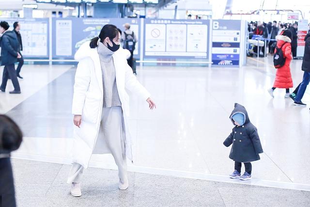 朱丹抱萌娃现身机场，身穿毛领白色羽绒服，清新时尚又保暖
