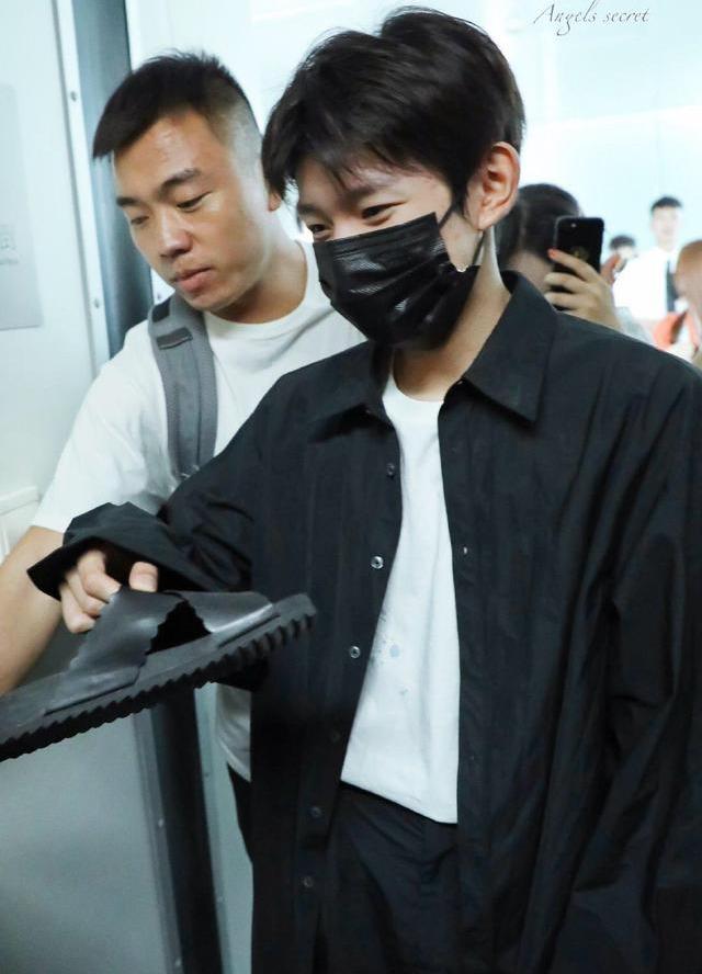 王源在机场帮粉丝捡拖鞋，表情像捡到了宝藏，眼睛都笑弯了